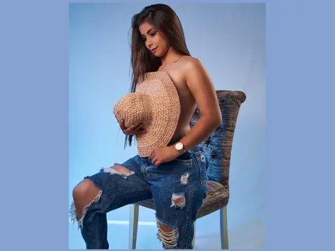 Princes_Jasmine — Princes_Jasmine sits on a chair wearing a tan tube top and ripped blue jeans, holding her large breasts.