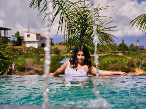 Princes_Jasmine — Princes_Jasmine with long dark hair poses in a swimming pool wearing a white tank top.