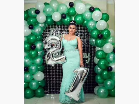 Princes_Jasmine — Princes_Jasmine poses in a light green lace dress next to silver number 21 balloons and a green balloon arch.