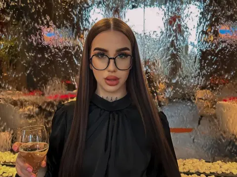 Stylish brunette woman in a black blouse and glasses holding a glass of rose wine in a glamorous setting.