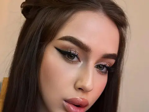 Young woman with glamorous winged eyeliner and shimmering eyeshadow makeup look in soft indoor lighting.