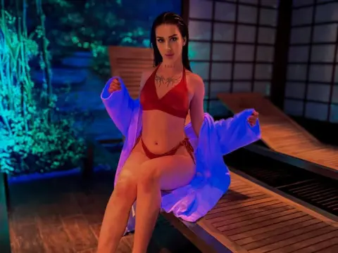 Young woman in a red bikini and blue robe relaxing on a wooden lounge chair in a moody, lit garden setting.