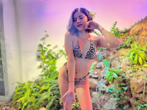 HoneyLia — Dreamy portrait of a woman in a leopard print bikini posing amidst lush tropical plants under soft pink lighting.