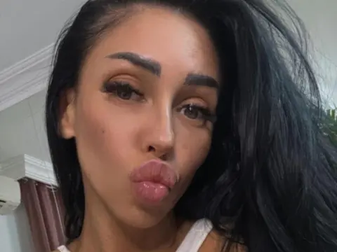 MyaBlakk — Close-up selfie of a woman with long dark hair and winged eyeliner making a pouty face in a bright indoor setting.