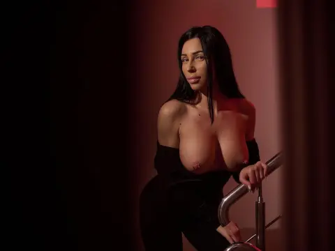 Young woman with long dark hair in a black outfit posing in moody red studio lighting.