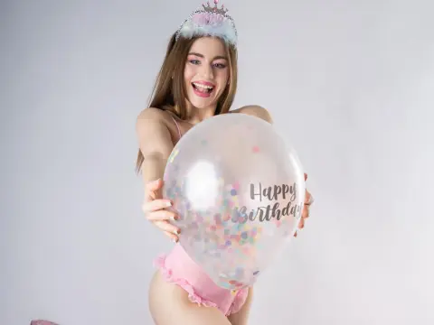 Cheerful young woman in pink lingerie holding a Happy Birthday balloon against a white studio background.