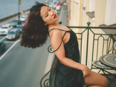 ErikaKim — ErikaKim poses on a balcony wearing a black silk slip dress, letting her long dark hair fall back while leaning against the black metal railing.