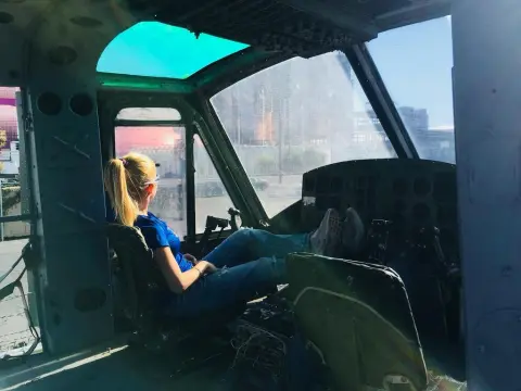 Exclusivegirl — Blonde woman in blue shirt relaxing in an old airplane cockpit looking out at the city view.