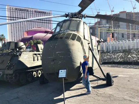 Exclusivegirl — Woman in blue shirt and jeans standing next to a vintage military transport helicopter in a sunny outdoor museum.