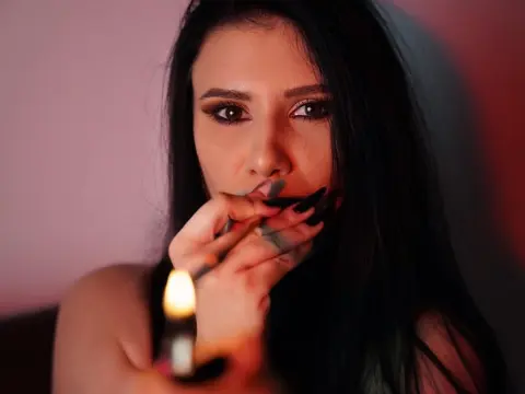 AlisiaChase — Mysterious woman with long dark hair holding a glowing candle in a moody, dimly lit setting.