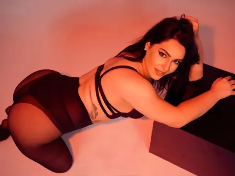 Curvy woman in black lingerie and tights posing in warm red studio lighting.