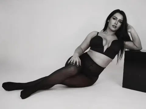 Elegant woman in black lingerie and tights posing against a white studio background with a moody aesthetic.