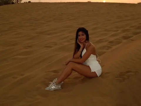 EvaBerryy — EvaBerryy sits on a sand dune at sunset wearing a white mini dress and white sneakers.