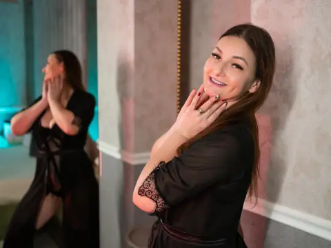 Smiling brunette woman in a black lace robe posing in a luxury bathroom setting.