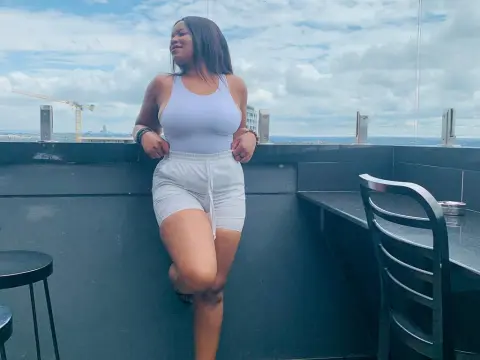 Smiling woman in a white tank top and shorts relaxing on a rooftop terrace under a cloudy sky.