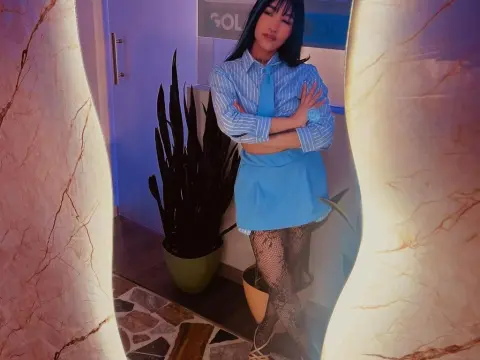 Stylish woman in a blue striped shirt and mini skirt posing in a modern interior with indoor plants.