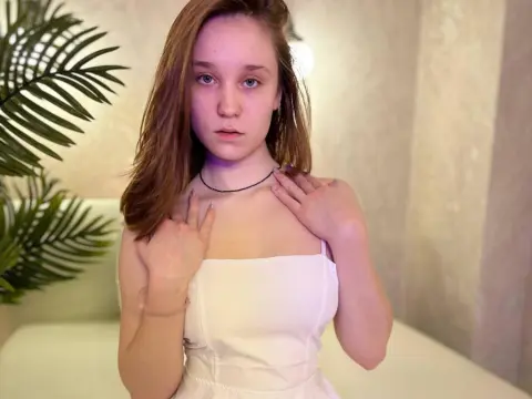 Young woman in a white strapless top posing with a serene expression against a neutral indoor background.