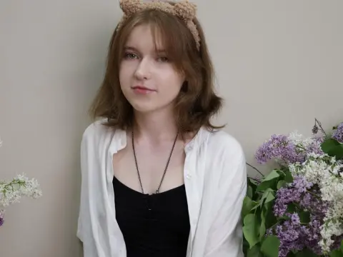 YukiPage — YukiPage wears a white shirt and black tank top while posing in front of purple lilacs.