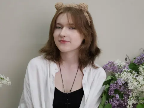 YukiPage — YukiPage wearing a white shirt and bear ears, posing next to purple lilac flowers.