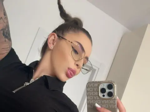 IvySins — IvySins pouts her lips while wearing large glasses and a black collared shirt, taking a mirror selfie with her phone.