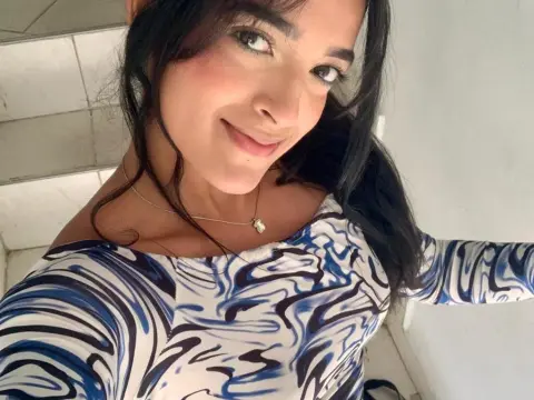 Smiling young woman in a blue and white patterned long-sleeve top posing indoors.