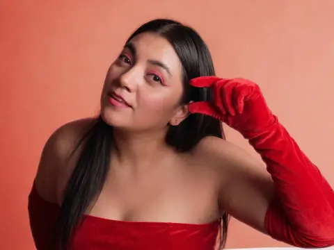 Glamorous woman in a red velvet dress and long gloves posing against a warm peach background.