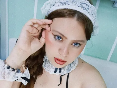 Woman in white lace lingerie and headband posing with a soft, romantic aesthetic in a bright room.