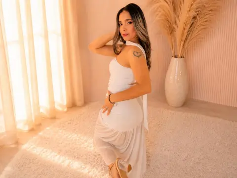 Young woman in a white summer dress posing in a sunlit, bohemian styled room with pampas grass decor.