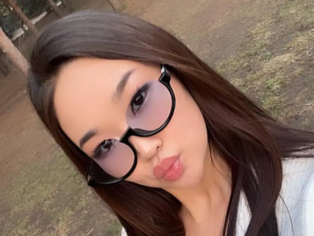 veryhotasiangirl1 pouts her lips while wearing black-rimmed glasses and looking at the camera with long dark hair.