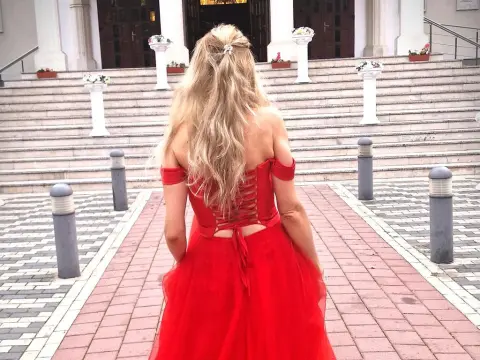 SpecialModelXXXX — Blonde woman in a flowing red off-the-shoulder gown walking up stone stairs toward a grand building.