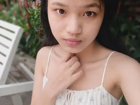 BabySweet18x — BabySweet18x looks at the camera wearing a white floral camisole with thin straps, posing outdoors with dark hair and a hand near her neck.
