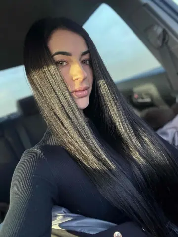 Karinabrunette — Karinabrunette poses in a car wearing a black long-sleeved top, showing off her long, straight black hair.