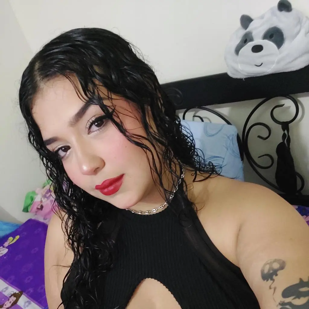 Jennadavonn poses with wet, wavy black hair wearing a black cutout top and a silver chain necklace.