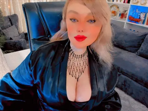ListenEtername — Blonde woman in a black satin robe and beaded necklace sitting on a sofa in a cozy living room.