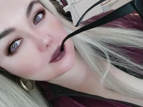 ListenEtername — Close-up selfie of a blonde woman with glamorous makeup wearing a dark burgundy leather jacket.