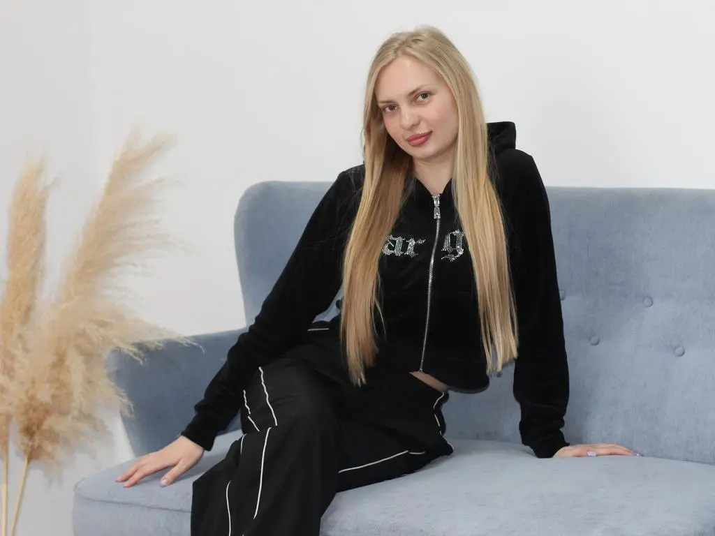 NancyTuun wearing a black zip-up hoodie and matching black pants while sitting on a light blue sofa.