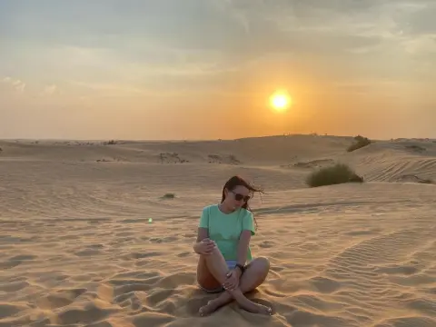 AmelyAngelx — Woman in a mint green t-shirt sitting on sand dunes during a golden sunset in the desert.
