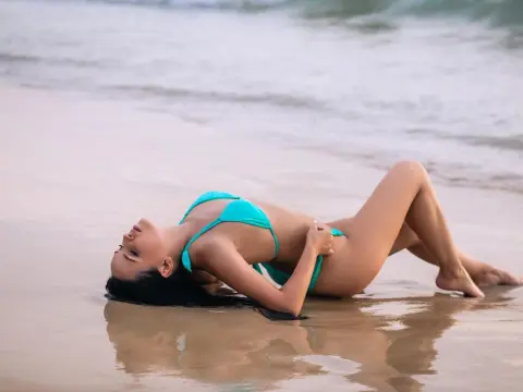 AmelyAngelx — Young woman in a turquoise bikini relaxing on a sandy beach at sunset with a peaceful mood.