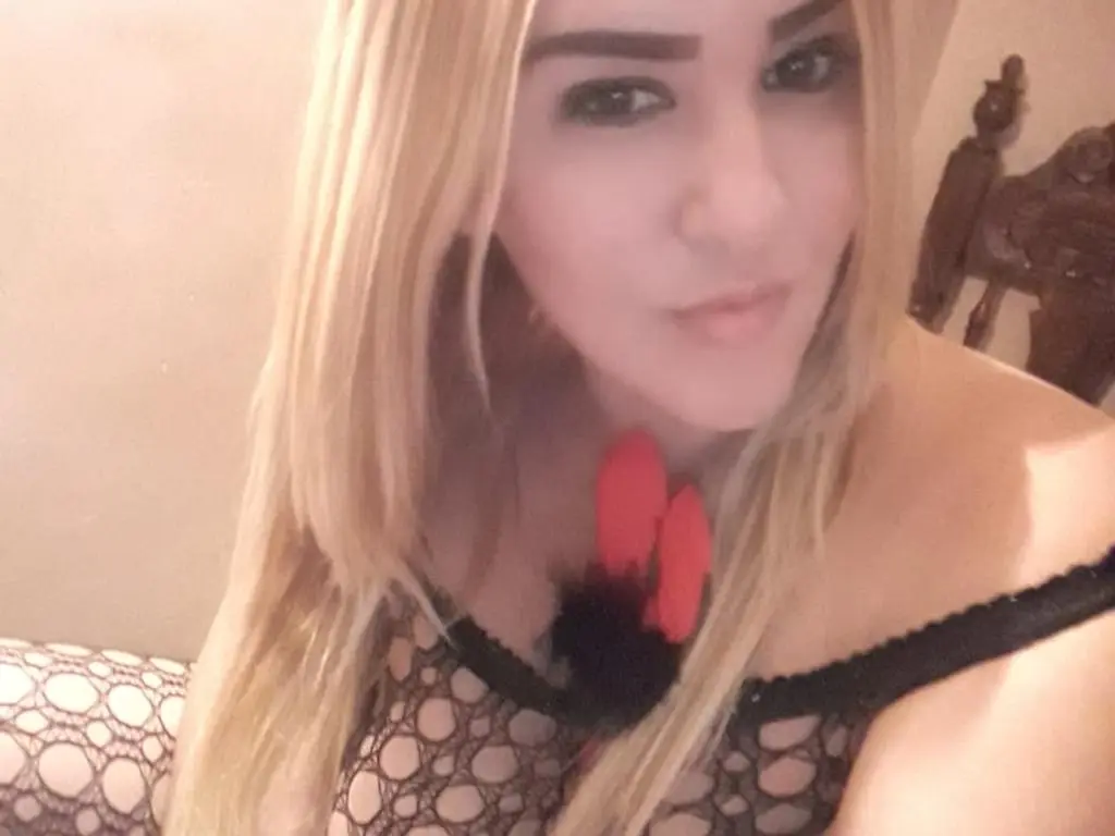 BIGHOTYBOOBS4 poses with her long blonde hair down, wearing a black lace mesh top with a red flower detail at her chest.