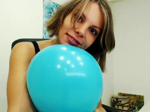 SexyPranks123 smiles while holding a large blue balloon close to her face in a close-up shot.
