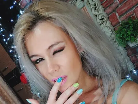 DevilMindXXX — Blonde woman with glamorous makeup posing in a cozy indoor setting with warm lighting.