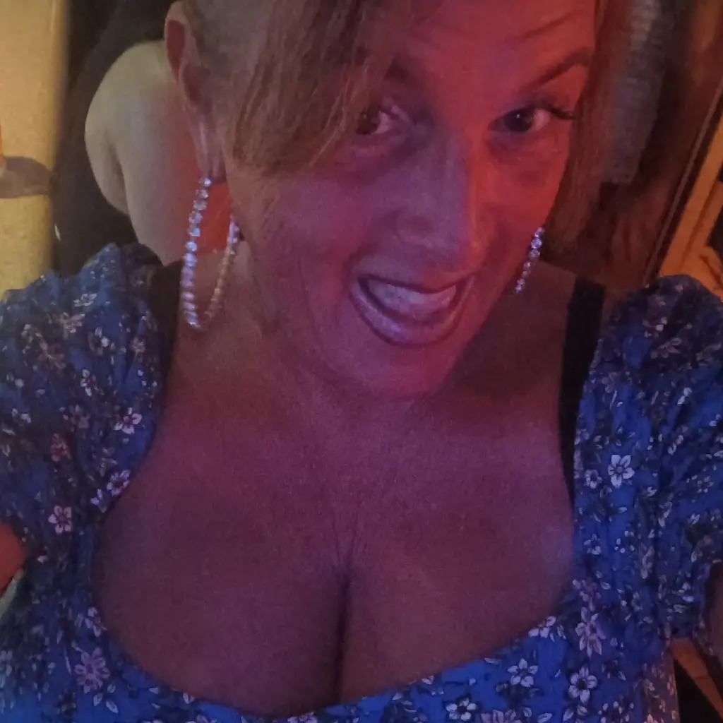 BBWgoDDDess — BBWgoDDDess smiles while wearing a blue floral print top and large silver hoop earrings.
