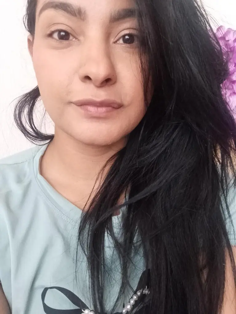 KisyLane — kisylane looks at the camera with her long black hair falling over her shoulder while wearing a light blue t-shirt.