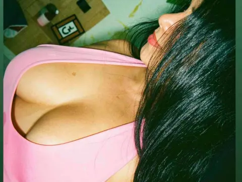QueenSofia — QueenSofia wears a pink tank top while looking toward the camera with her long dark hair falling over her shoulder.