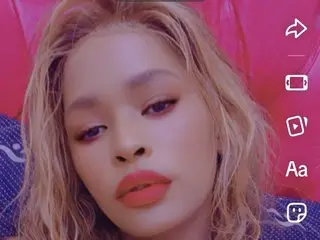 AFRICANGODDESSxxxxxx poses close-up, showing her face and blonde hair against a pink background.