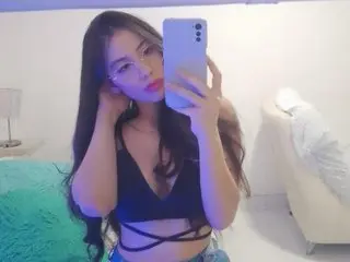 AMBEL_ROSE poses for a mirror selfie wearing a black v-neck crop top, showing her long brown hair and face.