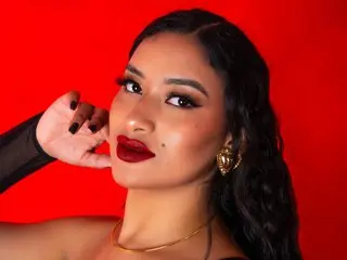 Glamorous woman with red lipstick and gold earrings posing against a vibrant red background.