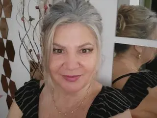 Adama4u smiles while looking at the camera, showing her blonde hair and a black striped top in a close-up shot.