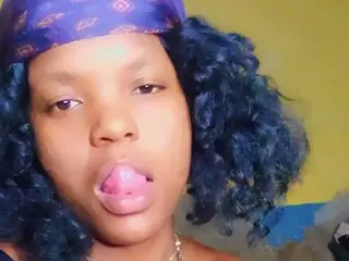 Young woman with blue curly hair and purple bandana making a playful expression indoors.