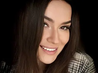 AliceOfWondersss poses with a close-up headshot, showing her long dark hair and a smile against a black background.